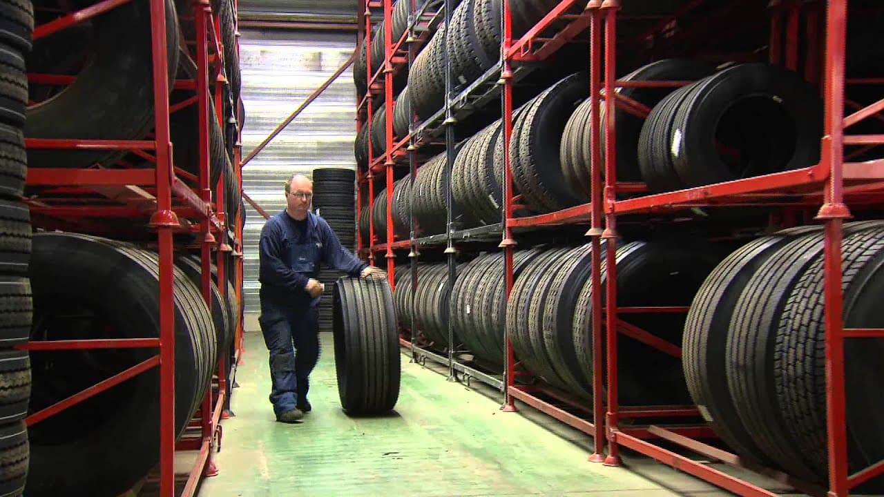 Still uit de bedrijfsfilm: een monteur bij het bandenrek in de werkplaats